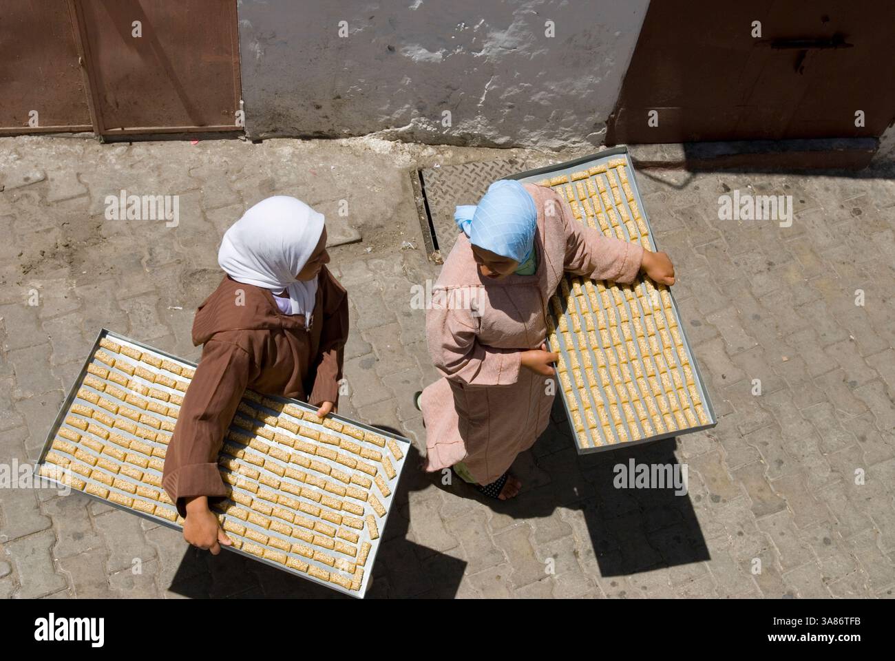 Femmes sur le chemin du four communal avec des gâteaux sur plateau, Médina, Tanger, Maroc Banque D'Images