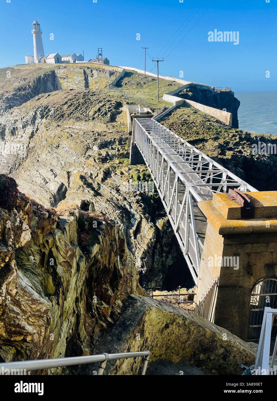 Vue spectaculaire du phare de South Stack, Anglesey, vue depuis les marches, vers Sea Stack Island passerelle couverte est au premier plan de la mer d'Irlande au-delà Banque D'Images