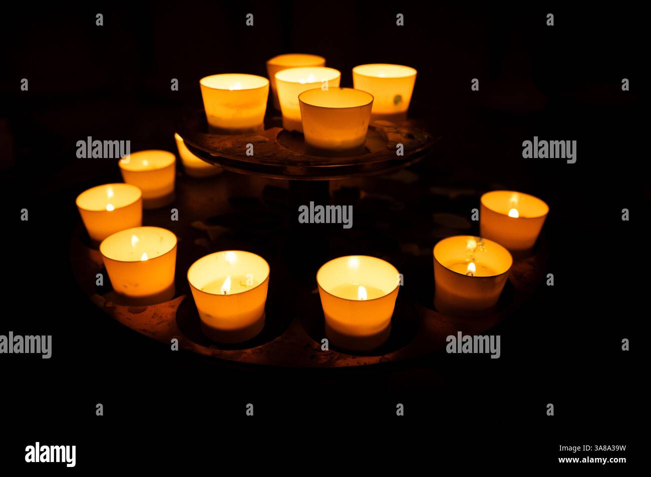 Gros plan de bougies qui brillent dans le noir à l'intérieur d'une église Banque D'Images