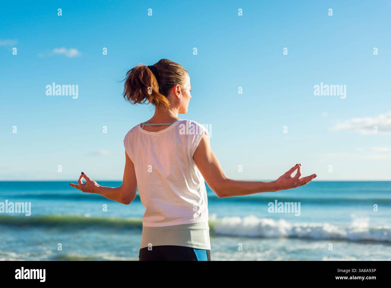 femme sportive pratiquant le yoga à la plage, debout méditant Banque D'Images femme sportive pratiquant le yoga à la plage, debout méditant Banque D'Images