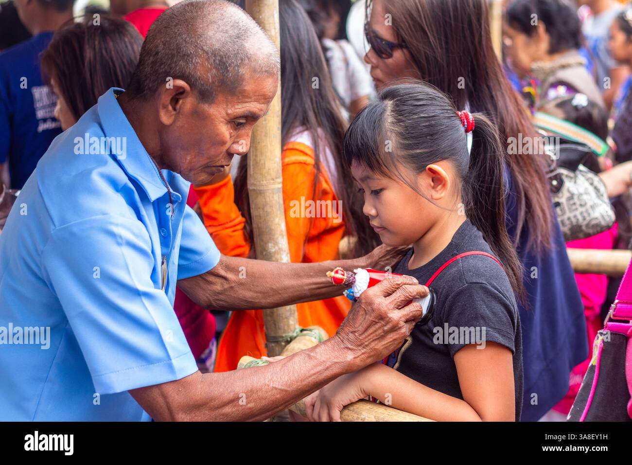 Un vieil homme bénit une fille philippine en touchant une image du Sto. Niño sur son front lors du Festival ATI-Atihan à Kalibo, Philippines Banque D'Images