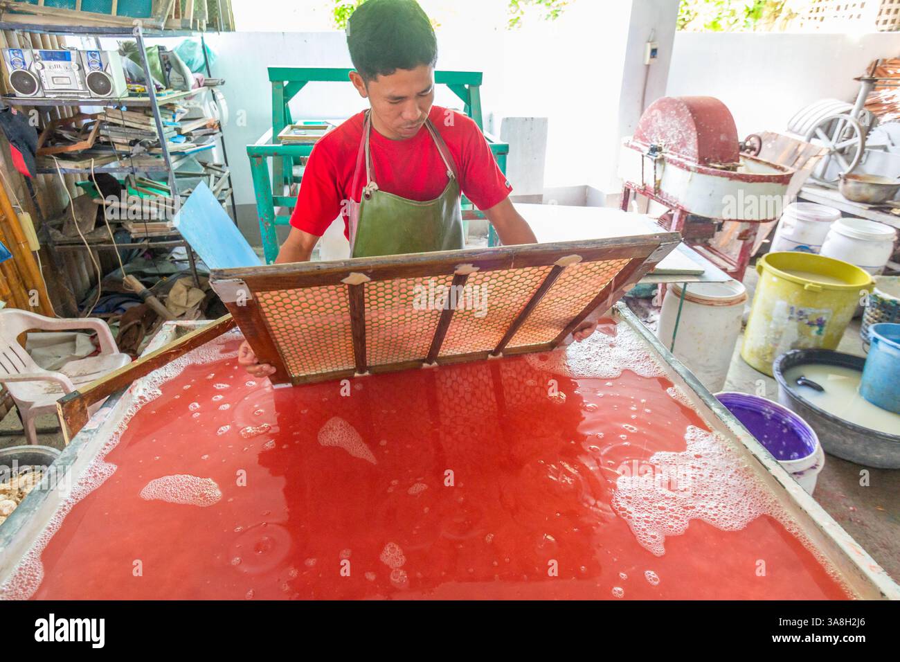 Un homme philippin fabrique du papier fait à la main dans une boutique d'artisanat à Kalibo, aux Philippines, en travaillant soigneusement avec de la pâte à papier et des outils traditionnels Banque D'Images