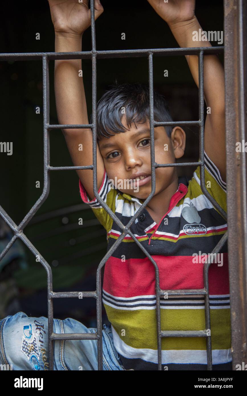 28 janvier 2012 - Khulna, Khulna, Bangladesh - Bangladesh, Khulna, colonie de balayeuses Sonadanga. La plupart de ces personnes qui vivent dans ce bidonville sont des Dalits hindous, ou la caste intouchable travaillant comme balayeuses et nettoyeuses de toilettes. Il y a environ 5,5 millions de Dalits à travers le pays, ce sont les castes les plus négligées dans leur société. Garçon jetant un coup d'œil à travers les barreaux de sa maison. (Crédit image : © Alison Wright via ZUMA Wire) Banque D'Images