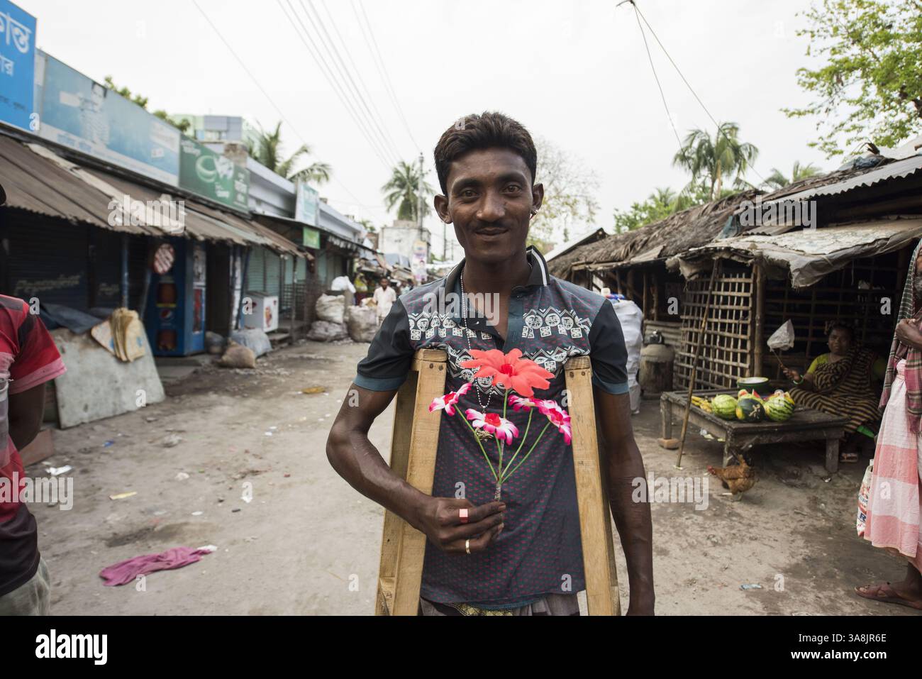 18 mars 2017 - Khulna, Khulna, Bangladesh - Bangladesh, Khulna, colonie de balayeuses Sonadanga. La plupart de ces personnes qui vivent dans ce bidonville sont des Dalits hindous, ou la caste intouchable travaillant comme balayeuses et nettoyeuses de toilettes. Il y a environ 5,5 millions de Dalits dans tout le pays, ce sont les castes les plus négligées de la société. Homme sur des béquilles avec des fleurs. (Crédit image : © Alison Wright via ZUMA Wire) Banque D'Images