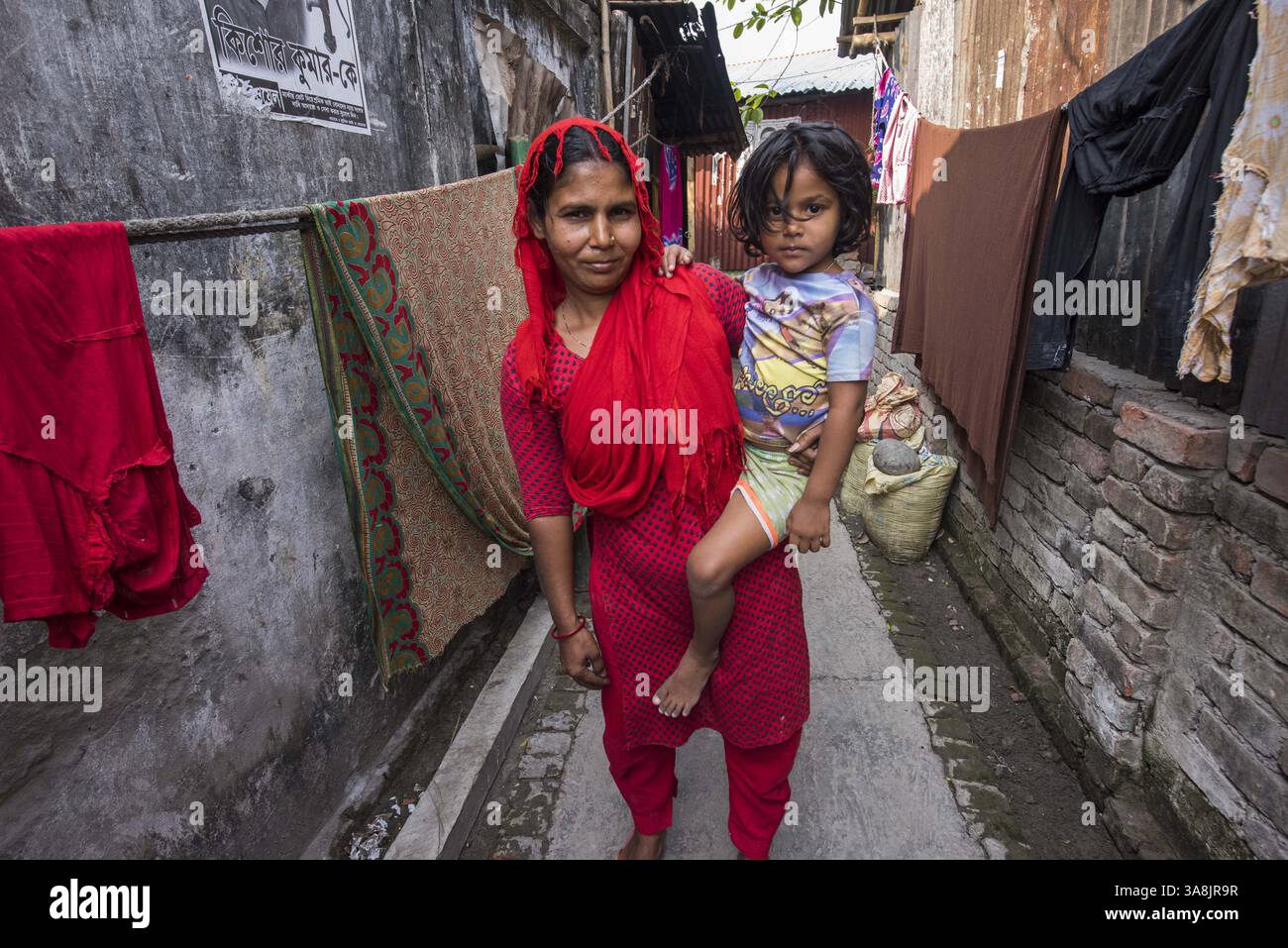 19 mars 2017 - Khulna, Khulna, Bangladesh - Bangladesh, Khulna, colonie de balayeuses Sonadanga. La plupart de ces personnes qui vivent dans ce bidonville sont des Dalits hindous, ou la caste intouchable travaillant comme balayeuses et nettoyeuses de toilettes. Il y a environ 5,5 millions de Dalits à travers le pays, ce sont les castes les plus négligées dans la société. Femme en rouge avec sa fille. (Crédit image : © Alison Wright via ZUMA Wire) Banque D'Images