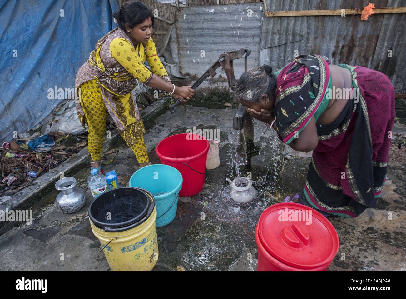 19 mars 2017 - Khulna, Khulna, Bangladesh - Bangladesh, Khulna, colonie de balayeuses Sonadanga. La plupart de ces personnes qui vivent dans ce bidonville sont des Dalits hindous, ou la caste intouchable travaillant comme balayeuses et nettoyeuses de toilettes. Il y a environ 5,5 millions de Dalits à travers le pays, ce sont les castes les plus négligées dans la société. Femmes pompant de l'eau au puits. (Crédit image : © Alison Wright via ZUMA Wire) Banque D'Images