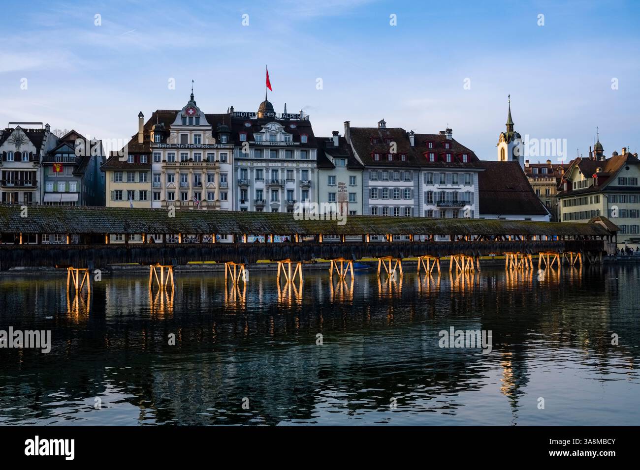 Vue sur la rivière Reuss jusqu'au pont de la Chapelle, façades d'hôtels et de maisons sur la rive de l'autre côté, au coucher du soleil. Banque D'Images