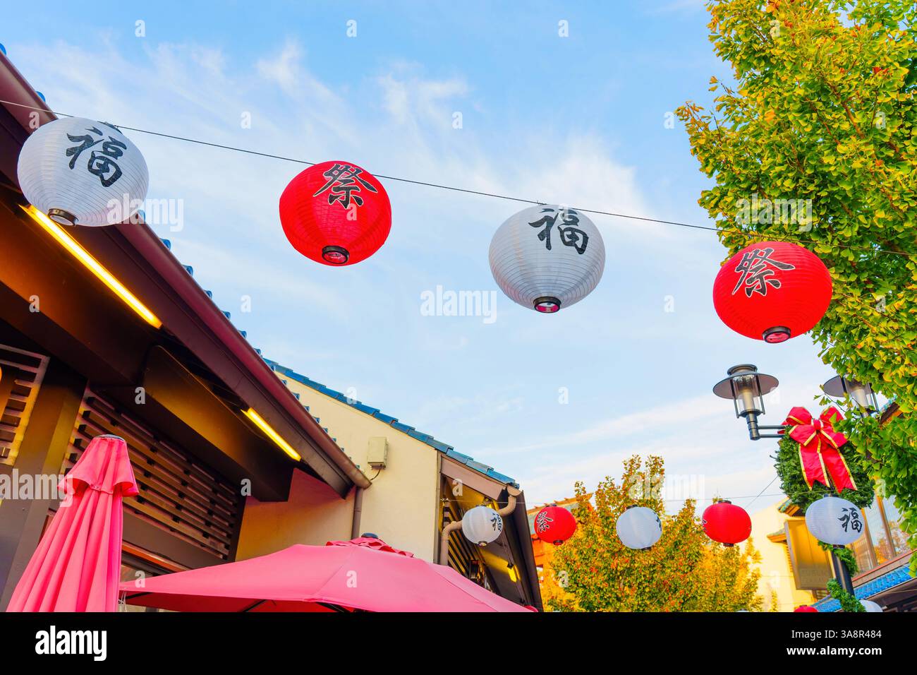 Los Angeles, Californie - 4 décembre 2024 : des lanternes rouges et blanches colorées sont suspendues au-dessus d'une rue animée de Little Tokyo, Los Angeles, illuminées par So Banque D'Images