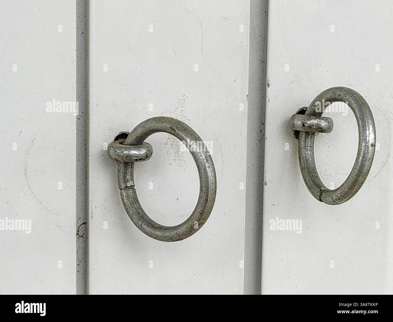 Anneaux de symétrie argentés , sur cadre de porte blanc. Banque D'Images