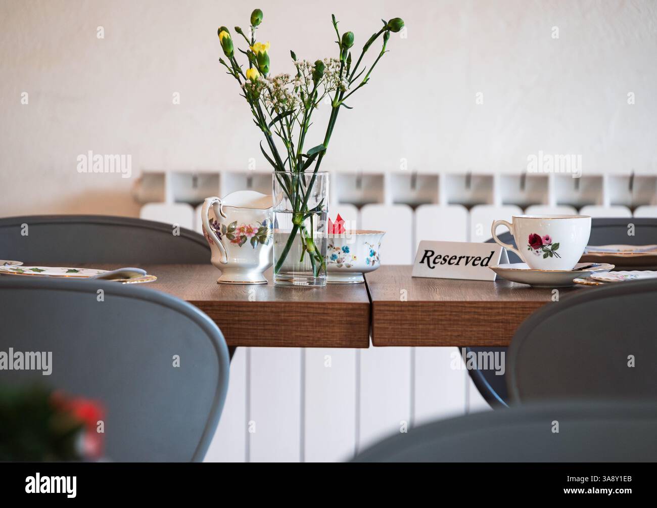 Une table réservée est fixée pour le thé de l'après-midi, avec de la porcelaine florale, un sucrier, une crémeuse et un vase de fleurs fraîches Banque D'Images