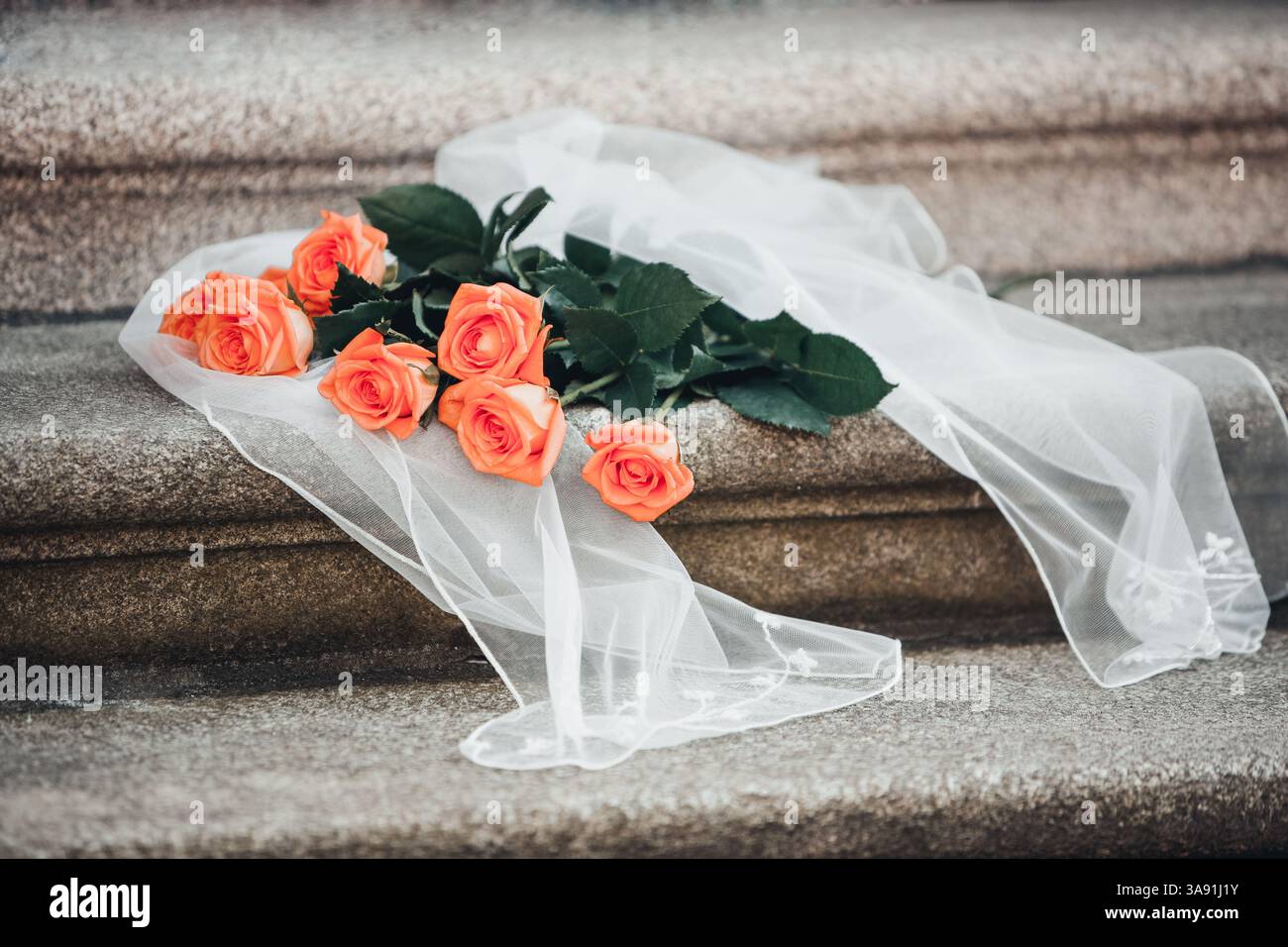 Un bouquet de roses orange est sur un tissu blanc sur un escalier. Les roses sont disposées de manière à ce qu'elles ne se touchent pas, et le tissu l'est Banque D'Images