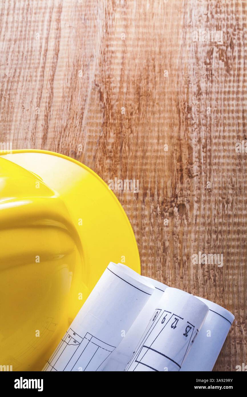 HardHat et plans roulés sur planche de bois brun gros plan avec copyspace Banque D'Images