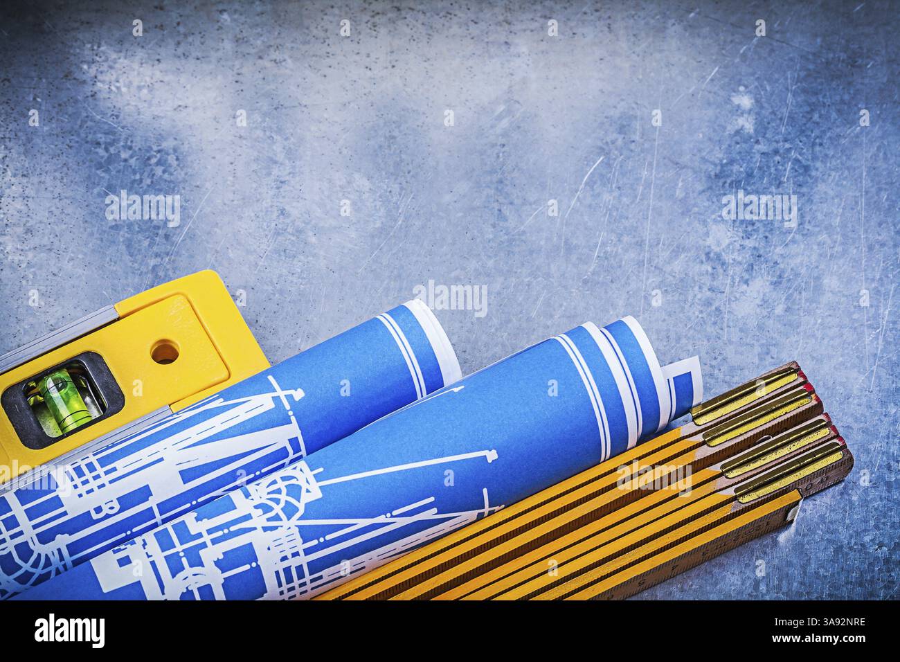 Mètre en bois bleu plans de construction roulés niveau sur fond métallique Banque D'Images
