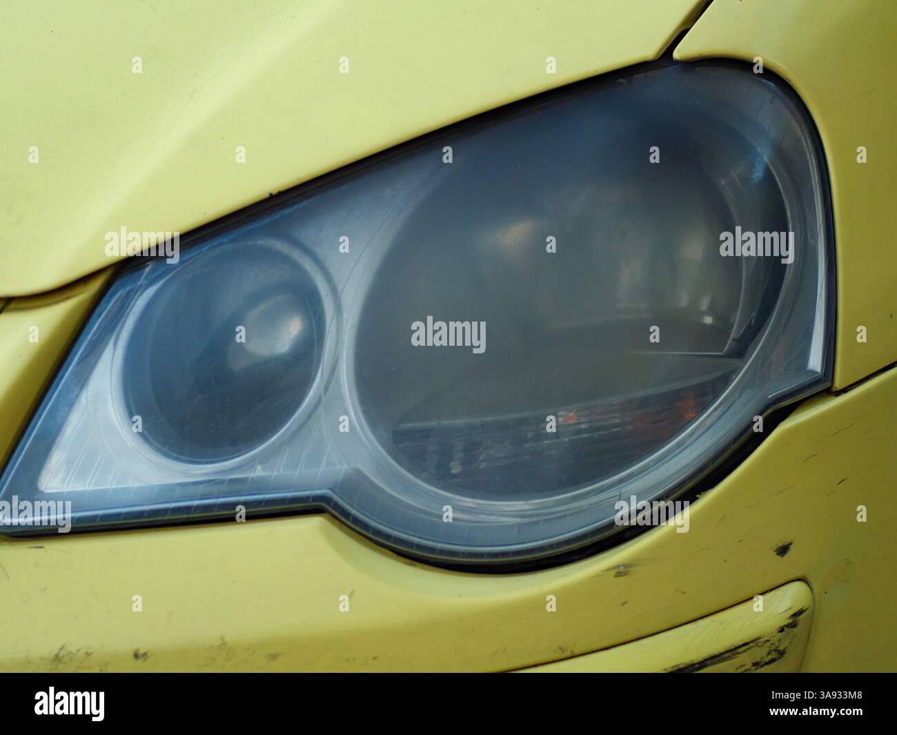 Gros plan détaillé du phare avant jauni d'une vieille Volkswagen Polo, mettant en évidence l'usure et l'âge de l'éclairage de la voiture. Banque D'Images
