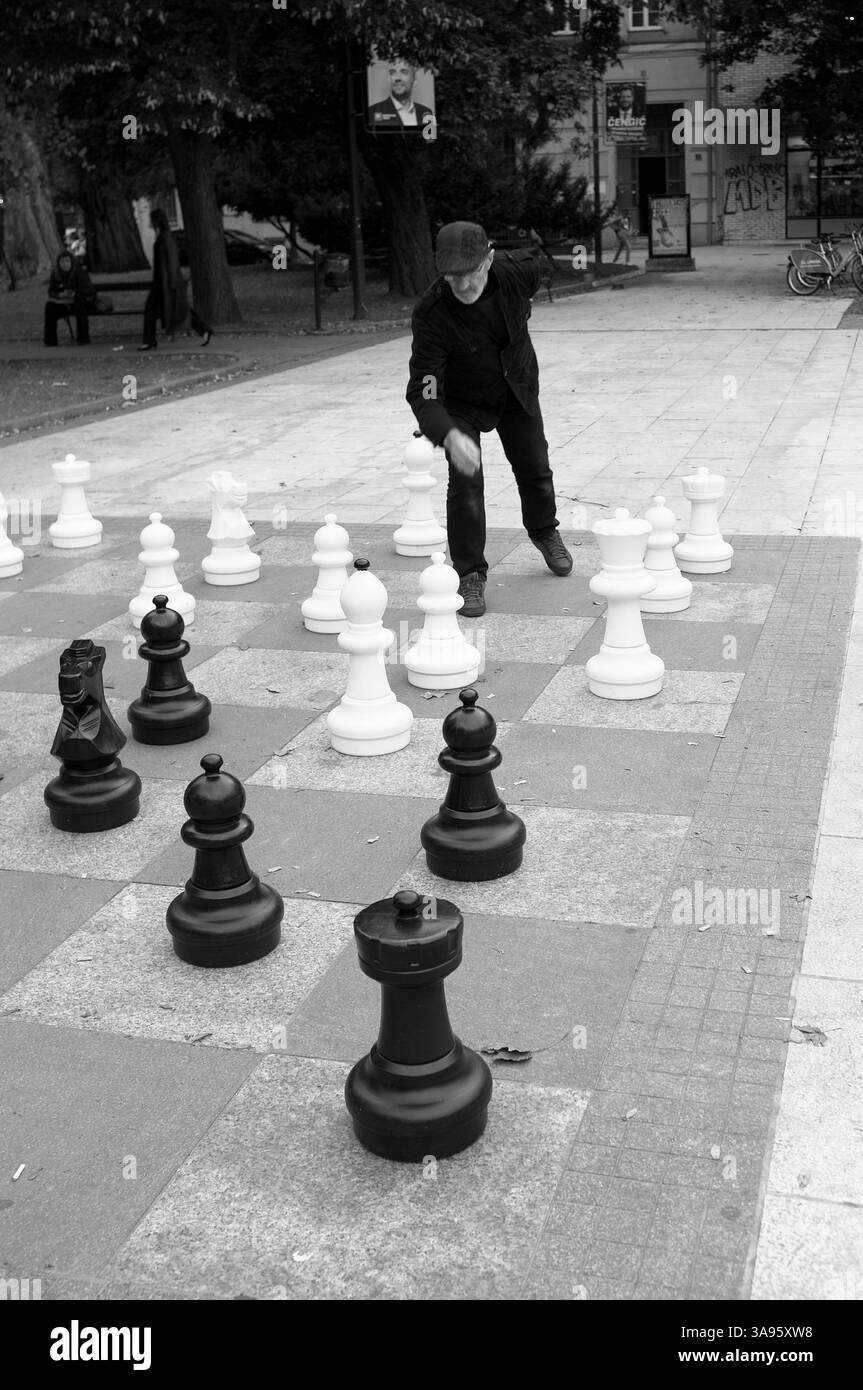 Photographie en noir et blanc jeune homme et plus âgé jouant un match de rue avec des échecs géants à Sarajevo, Bosnie-Herzégovine (séquence 1/5 ; à la fin de Banque D'Images