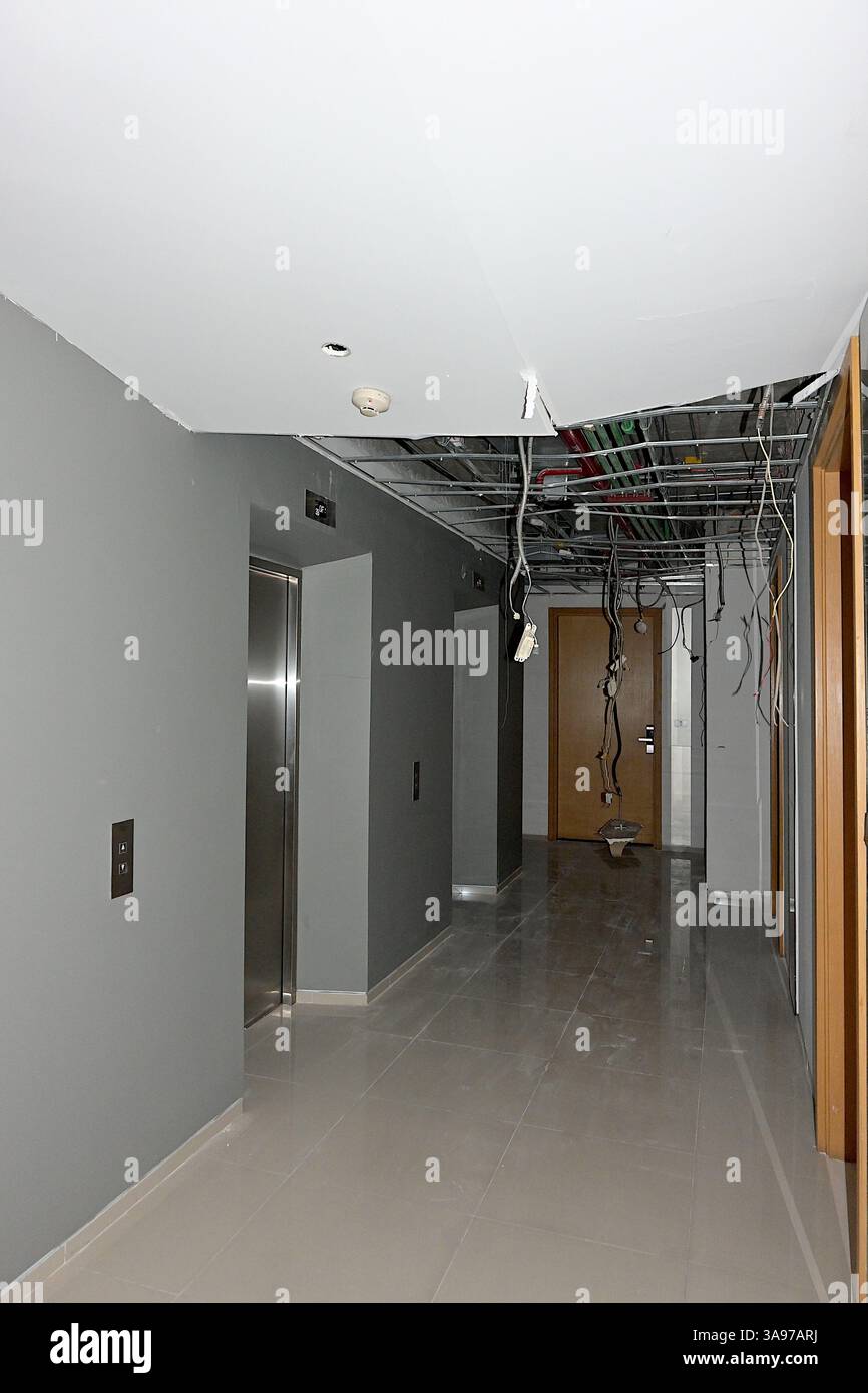 Couloir non éclairé avec panneau de faux plafond endommagé et câblage exposé dans un condo haut de gamme de Bangkok suite au tremblement de terre du 28 mars au Myanmar Banque D'Images