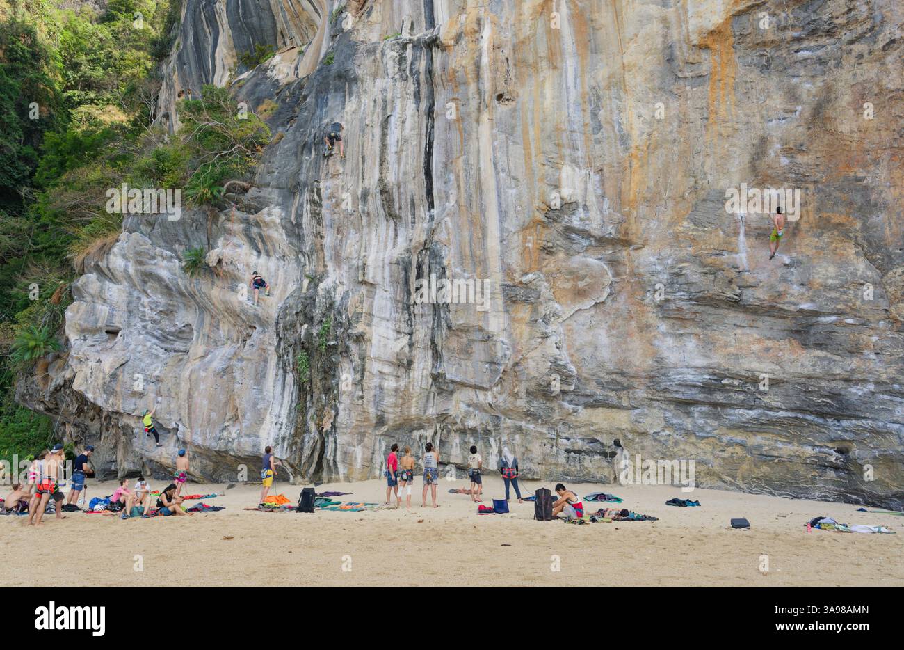 Les grimpeurs escaladent les falaises calcaires de Tonsai Beach tandis que d'autres se préparent ou se détendent sur le sable en contrebas Banque D'Images