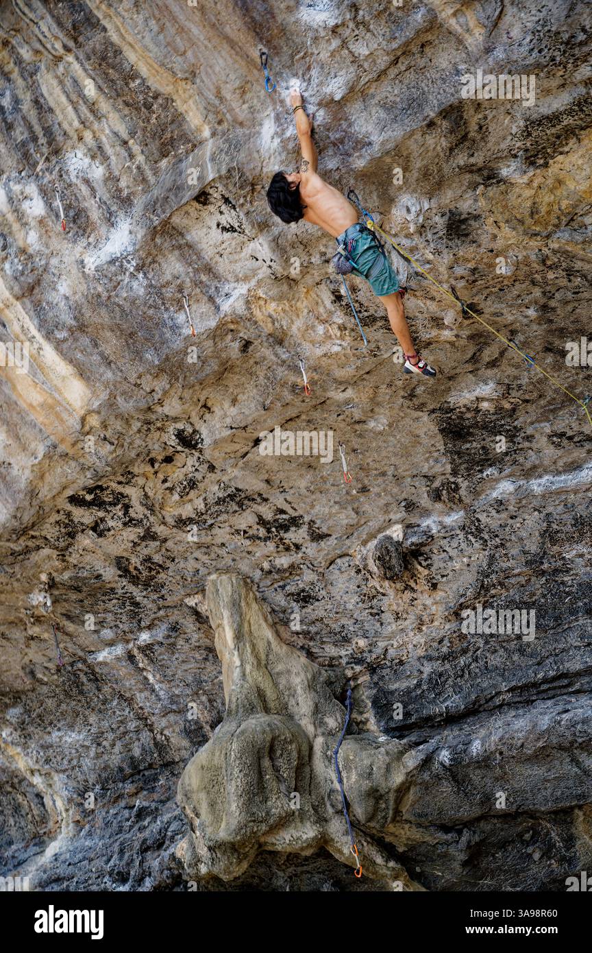 Jeune grimpeur atteint pour une prise lointaine sur un surplomb raide à Tonsai Banque D'Images
