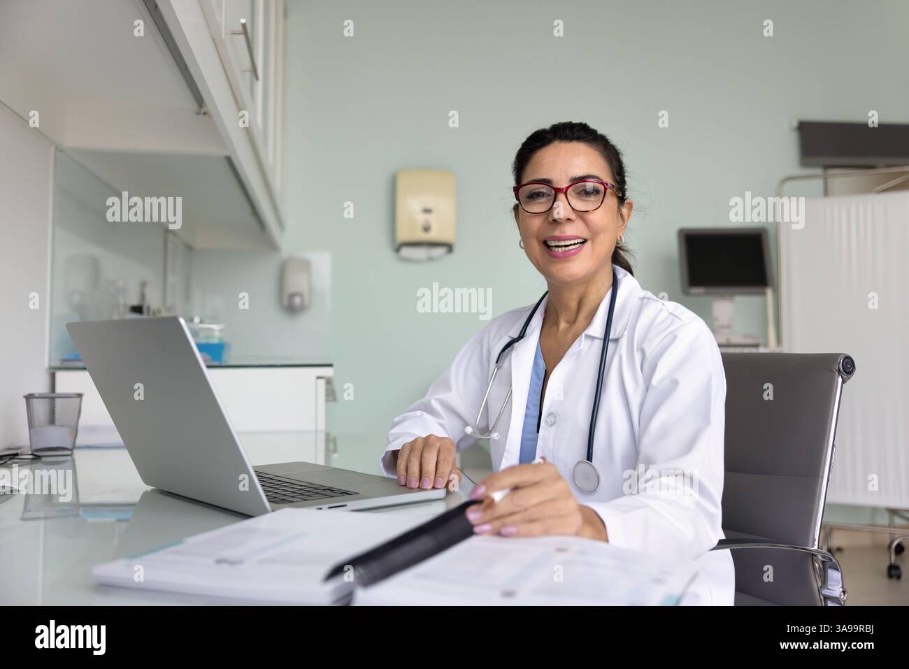 Heureuse femme médecin professionnelle médicale mature assise sur le lieu de travail Banque D'Images