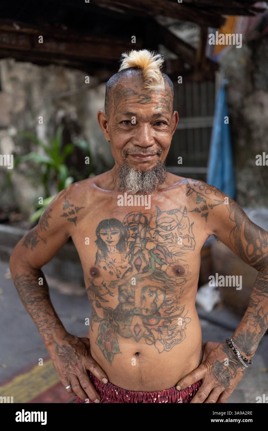 Un homme avec des tatouages et une coiffure Mohican, l'un des nombreux personnages colorés vivant dans le quartier Talat Noi, Bangkok, Thaïlande, Asie. Banque D'Images