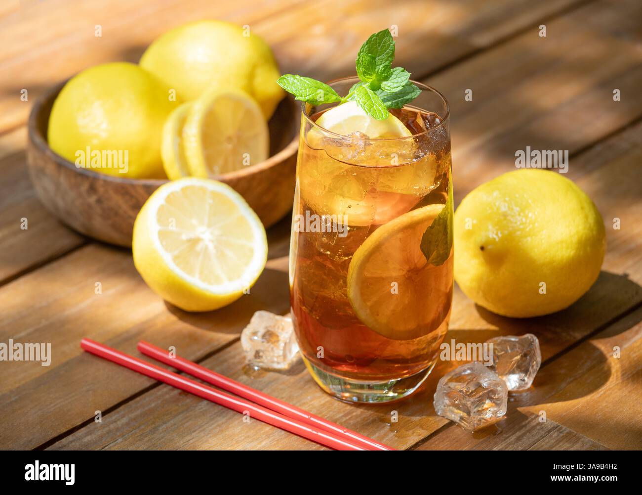 Verre de thé glacé avec des tranches de citron et de menthe et citrons frais à l'extérieur sur une table en bois Banque D'Images
