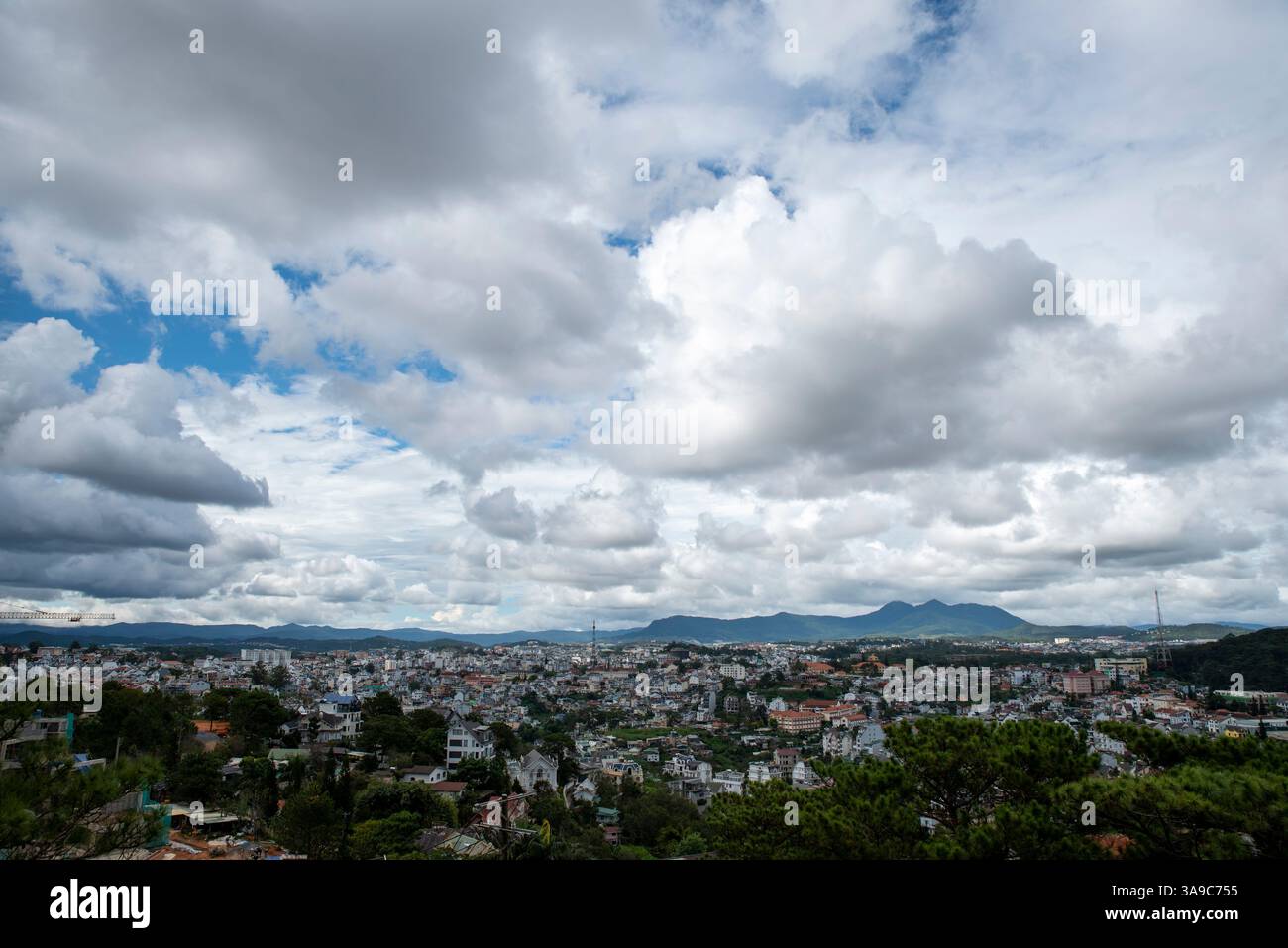 Une ville avec un ciel nuageux en arrière-plan. Le ciel est principalement nuageux avec quelques taches de bleu Banque D'Images