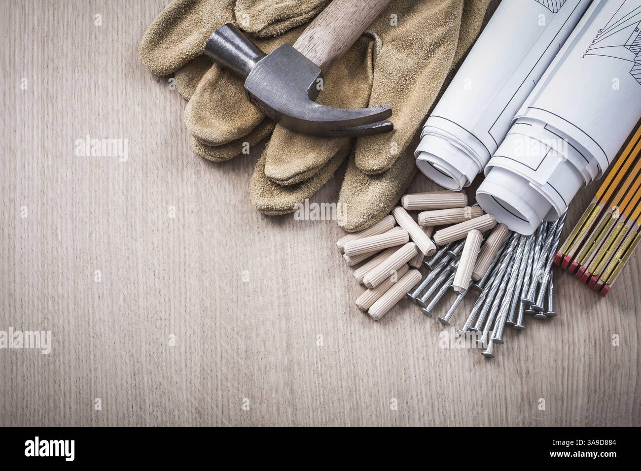 Chevilles de compteur en bois rouleaux bleus griffes marteau gants de protection en cuir et clous en métal sur le concept de construction de panneaux de bois Banque D'Images