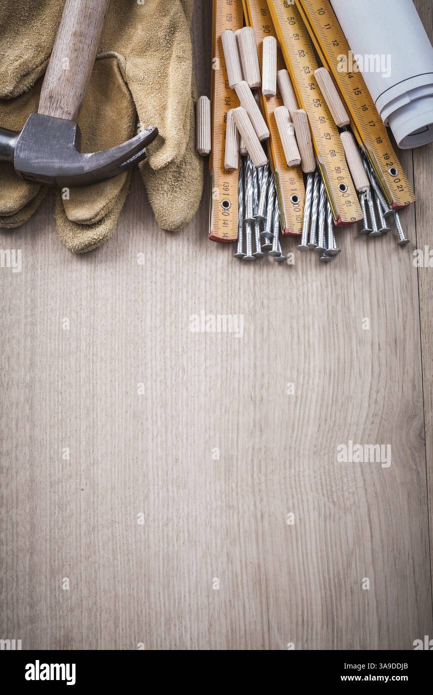 Chevilles de compteur en bois Blueprints marteau paire de gants de protection et clous en métal sur le concept de construction de vue verticale de planche de bois Banque D'Images