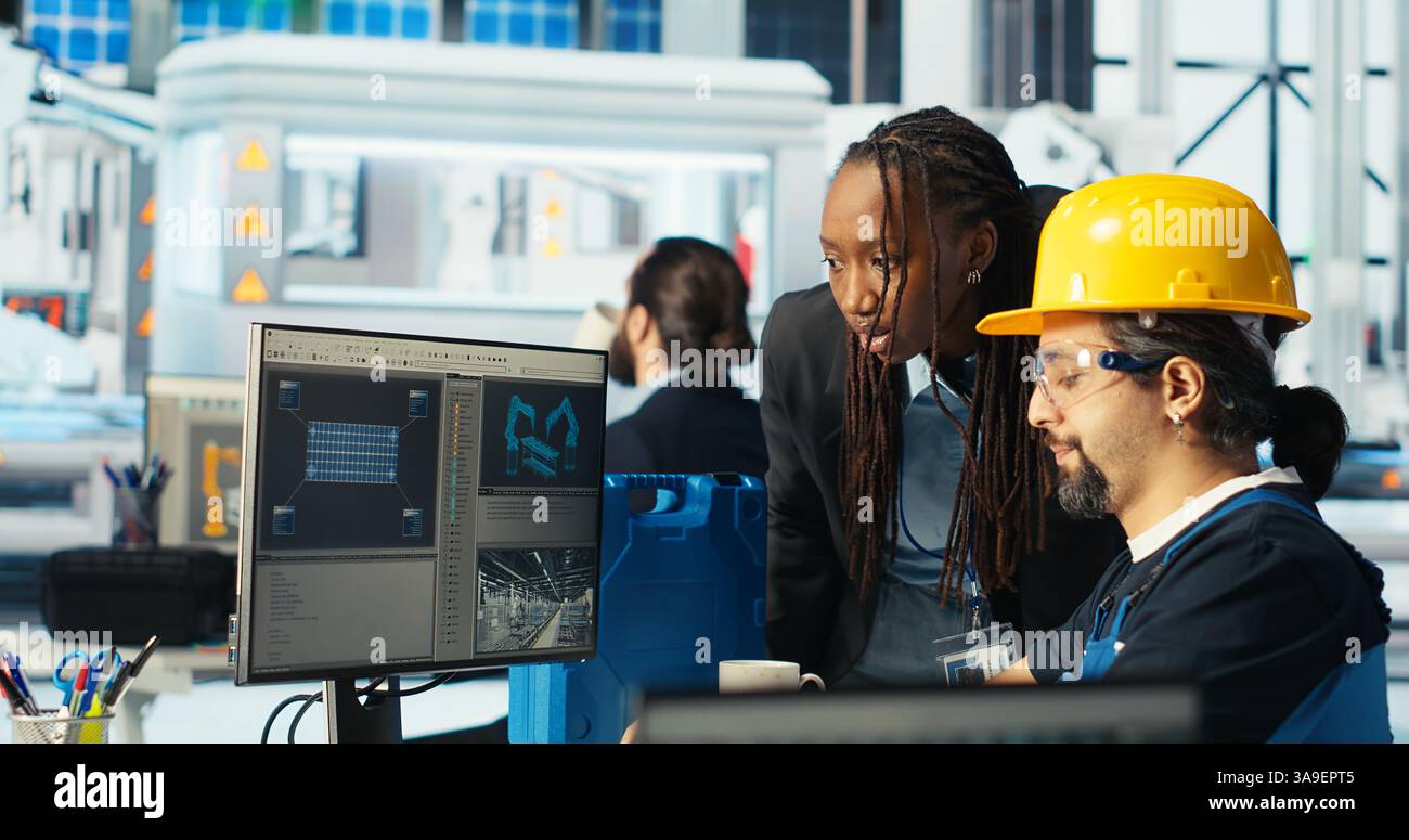 Expert de l'usine de panneaux solaires instruisant le technicien comment exploiter au mieux l'énergie solaire. Usine photovoltaïque chercheur afro-américain montre aux travailleurs comment améliorer l'efficacité, caméra B. Banque D'Images
