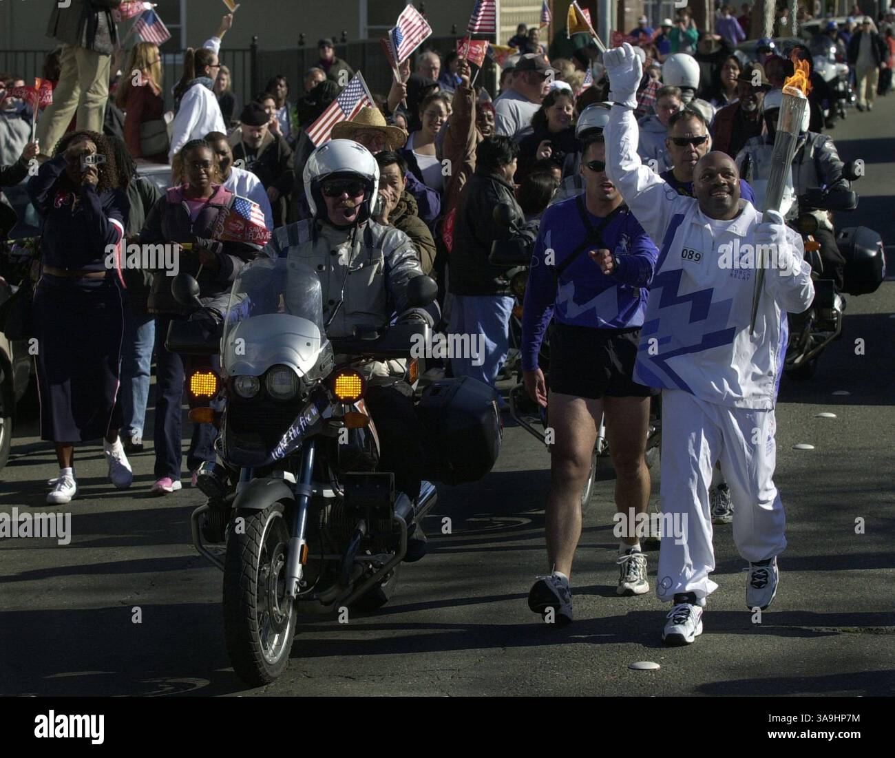19 janvier 2002 ; Richmond, CA, États-Unis ; Ken carter, professeur et entraîneur de l’école secondaire de Richmond, fait signe de la vague à la foule alors qu’il porte la flamme olympique dans les rues de Richmond, Calif, le samedi 19 janvier 2002. Banque D'Images