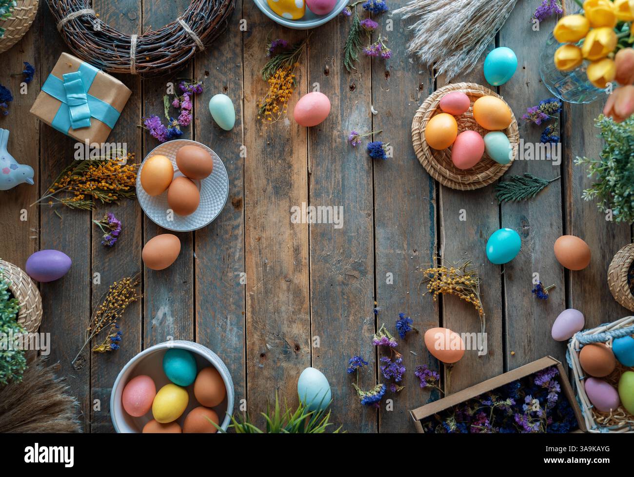 Fond de vacances de Pâques. Oeufs colorés et fleurs sur la table en bois. Vue de dessus Banque D'Images