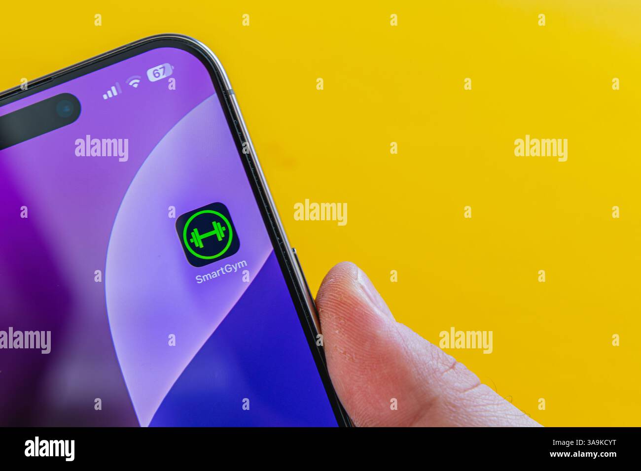 03.26.25 Lviv Ukraine Une personne tient un smartphone avec une icône d'application de fitness sur un fond jaune vif, mettant en évidence le technolog avancé Banque D'Images