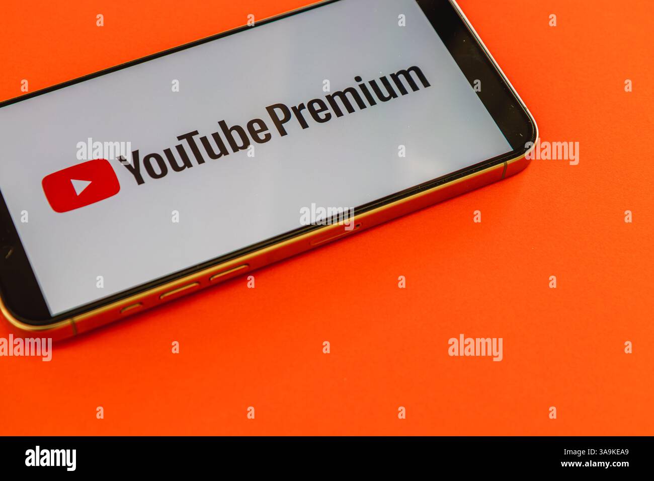 03.26.25 Lviv Ukraine Un téléphone intelligent arbore le logo YouTube Premium sur fond orange vif, mettant en valeur le contenu attrayant de la plateforme Banque D'Images