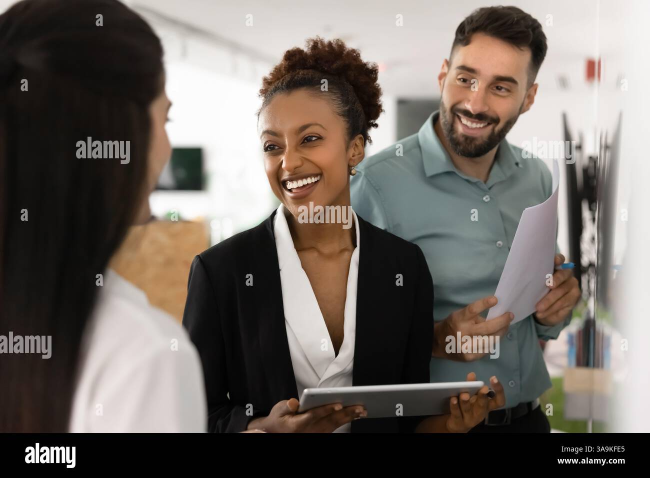 Partenaires commerciaux heureux et diversifiés discutant au tableau blanc, discutant de la collaboration Banque D'Images