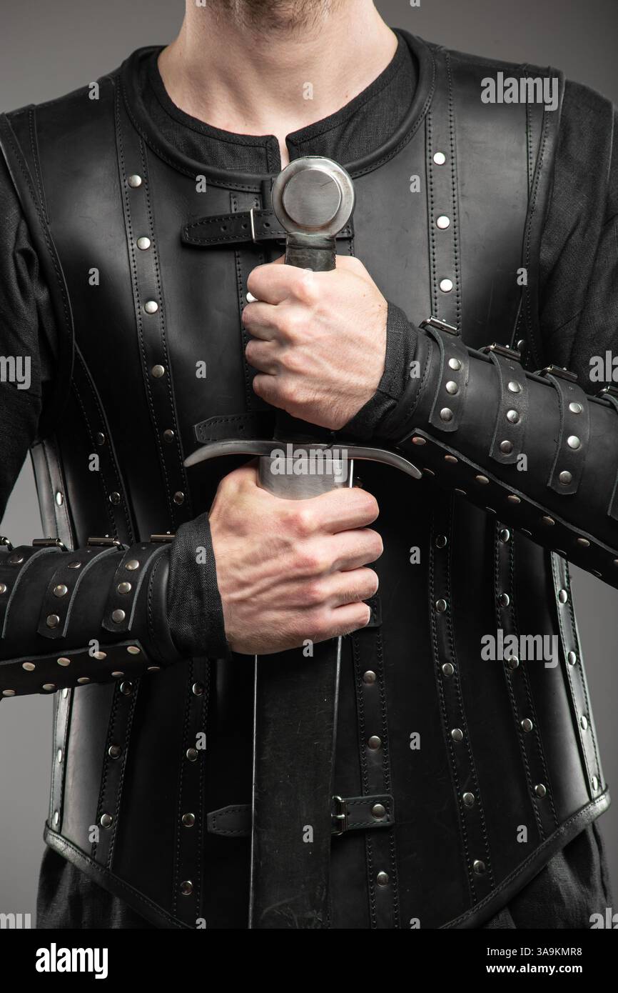 Personne portant des bracelets en cuir de veuve noire tenant l'épée Banque D'Images