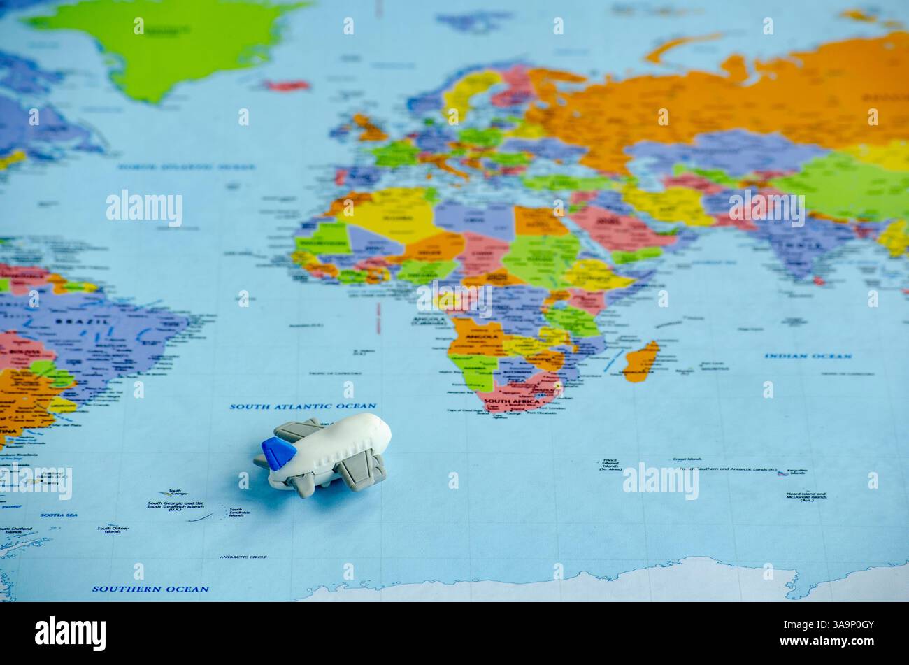 Vue de dessus d'un petit avion jouet placé sur une carte du monde représentant un voyage ou une exploration globale. Concept de voyage et de destination. Banque D'Images