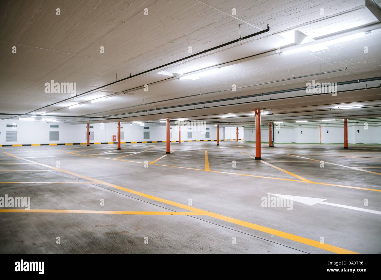 Parking souterrain vide et éclairé. Vue grand angle, pas de gens, pas de voitures. Banque D'Images