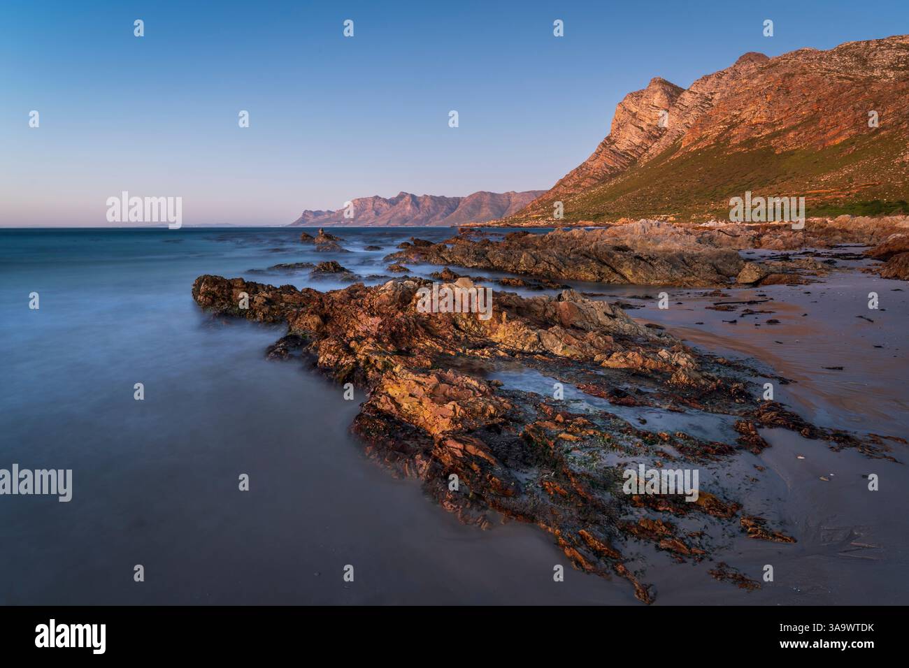 Vues en soirée vers Gordons Bay et les montagnes de Kogelberg à travers False Bay depuis la plage de Rooi-Els près du Cap, Western Cape. Afrique du Sud. Banque D'Images