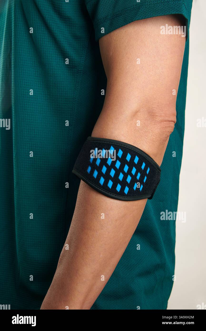 un athlète, portant un t-shirt de sport vert, porte un bracelet épicondylite sur son bras, pour soulager la douleur de l'épicondylite, également connu sous le nom de tennis e Banque D'Images