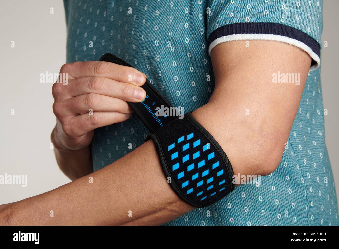 gros plan d'un homme ajustant son bracelet d'épicondylite sur son bras, pour soulager la douleur de l'épicondylite, également connu sous le nom de tennis elbow Banque D'Images