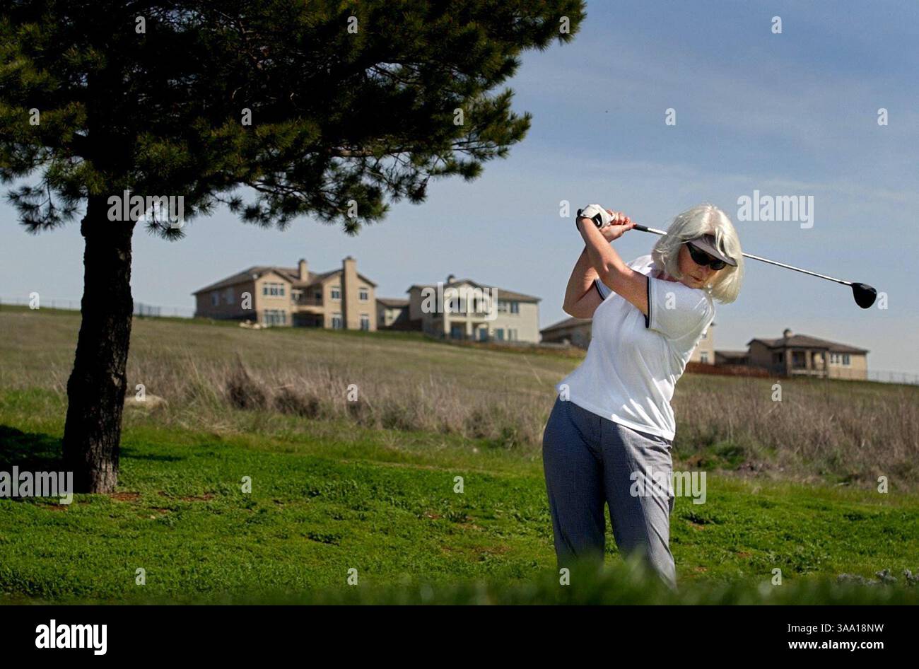 Jamie Brockardt (CQ) de Fair Oaks retire la pilote pour son tir au sixième trou du terrain de golf El Dorado Hills jeudi 21 février 2002. Le parcours vieux de 40 ans, qui s'adresse principalement aux personnes âgées et aux jeunes, a du mal à s'intégrer au marché du golf d'aujourd'hui, avec la prolifération de nouveaux parcours plus difficiles. Les revenus sont en baisse, la concurrence est en hausse, et cette vénérable course devrait se terminer plus tard cette année. En arrière-plan, de nouvelles maisons sont construites dans le développement Serrano, ce qui contribue également à la disparition éventuelle du parcours. (Sacramento Bee/Chr Banque D'Images