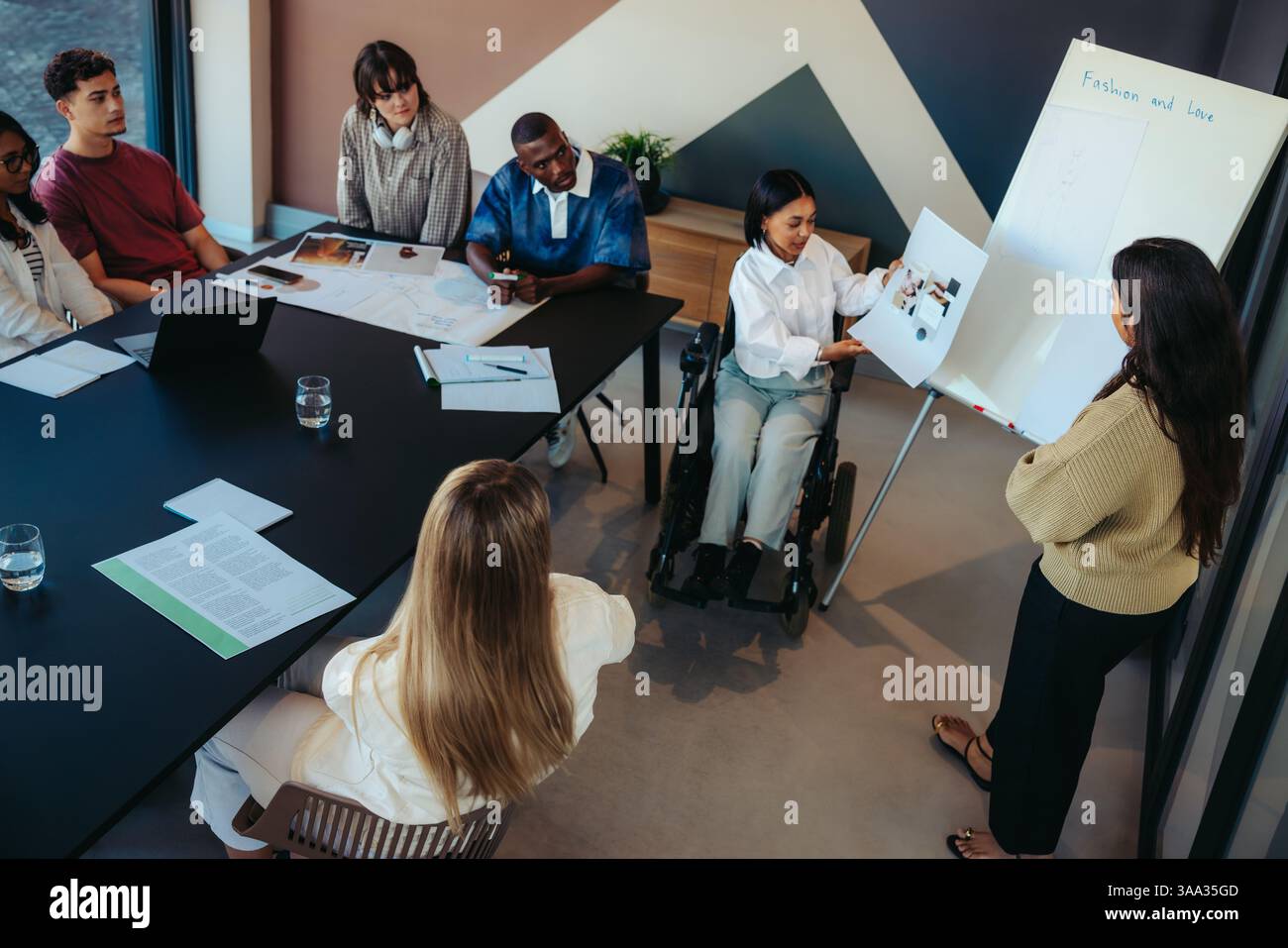 Étudiants engagés dans une présentation sur la mode et l'amour par une femme en fauteuil roulant, soulignant l'accessibilité dans le cadre de la classe avec PA diversifié Banque D'Images
