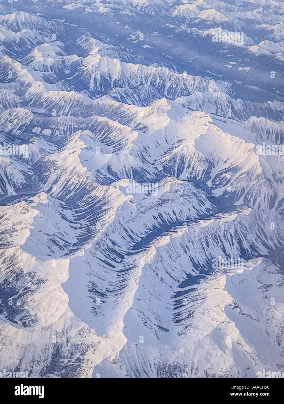 Prise de vue aérienne capturant une vaste chaîne de montagnes enneigée avec des sommets nets et un terrain accidenté. Paysage hivernal à couper le souffle vu d'en haut. - Image de stock capturée avec un smartphone