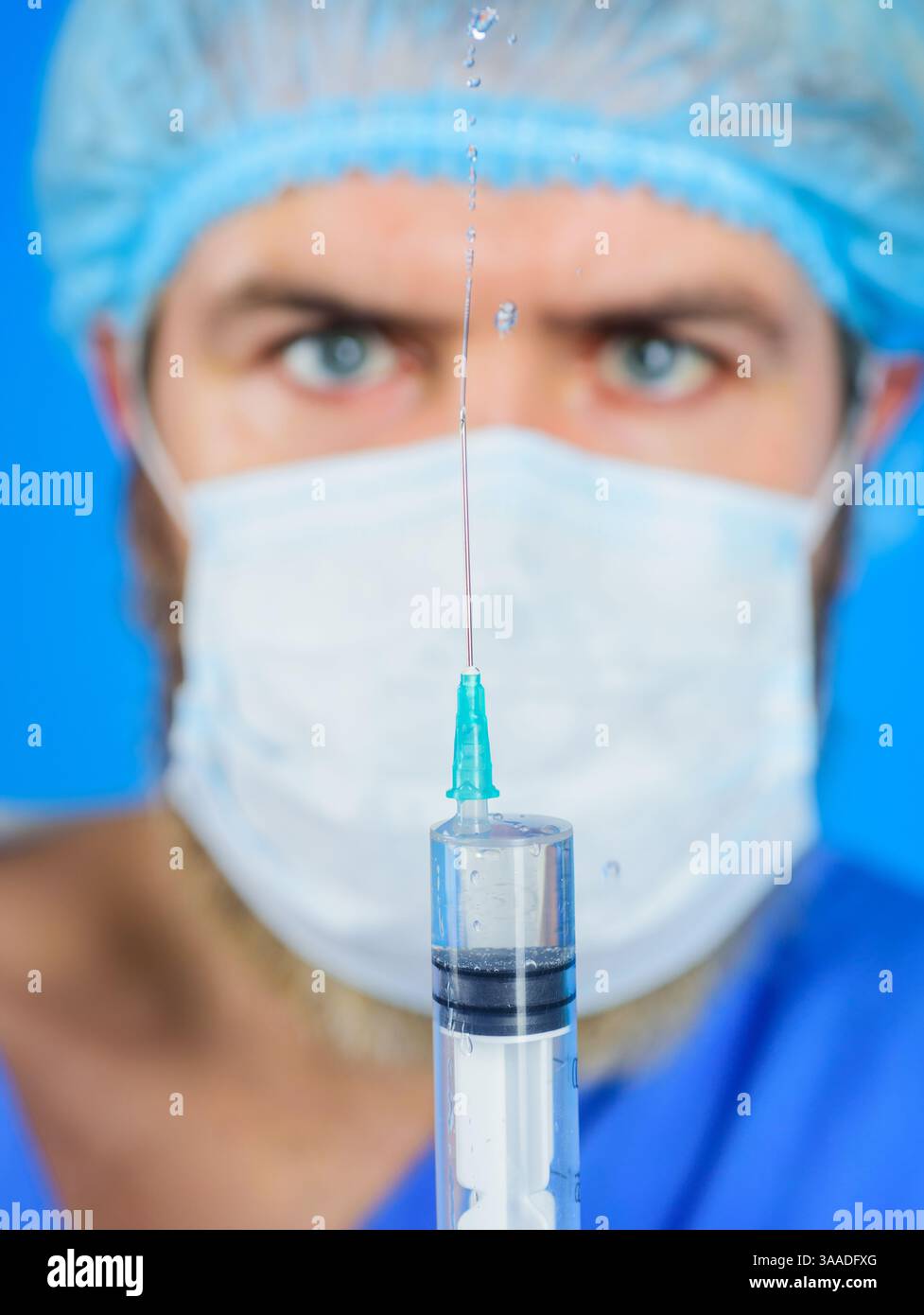 Médecin masculin dans le masque chirurgical préparant la seringue avec l'aiguille pour l'injection. Mise au point sélective. Le médecin tient une seringue de giclage avec des médicaments. Vaccination Banque D'Images