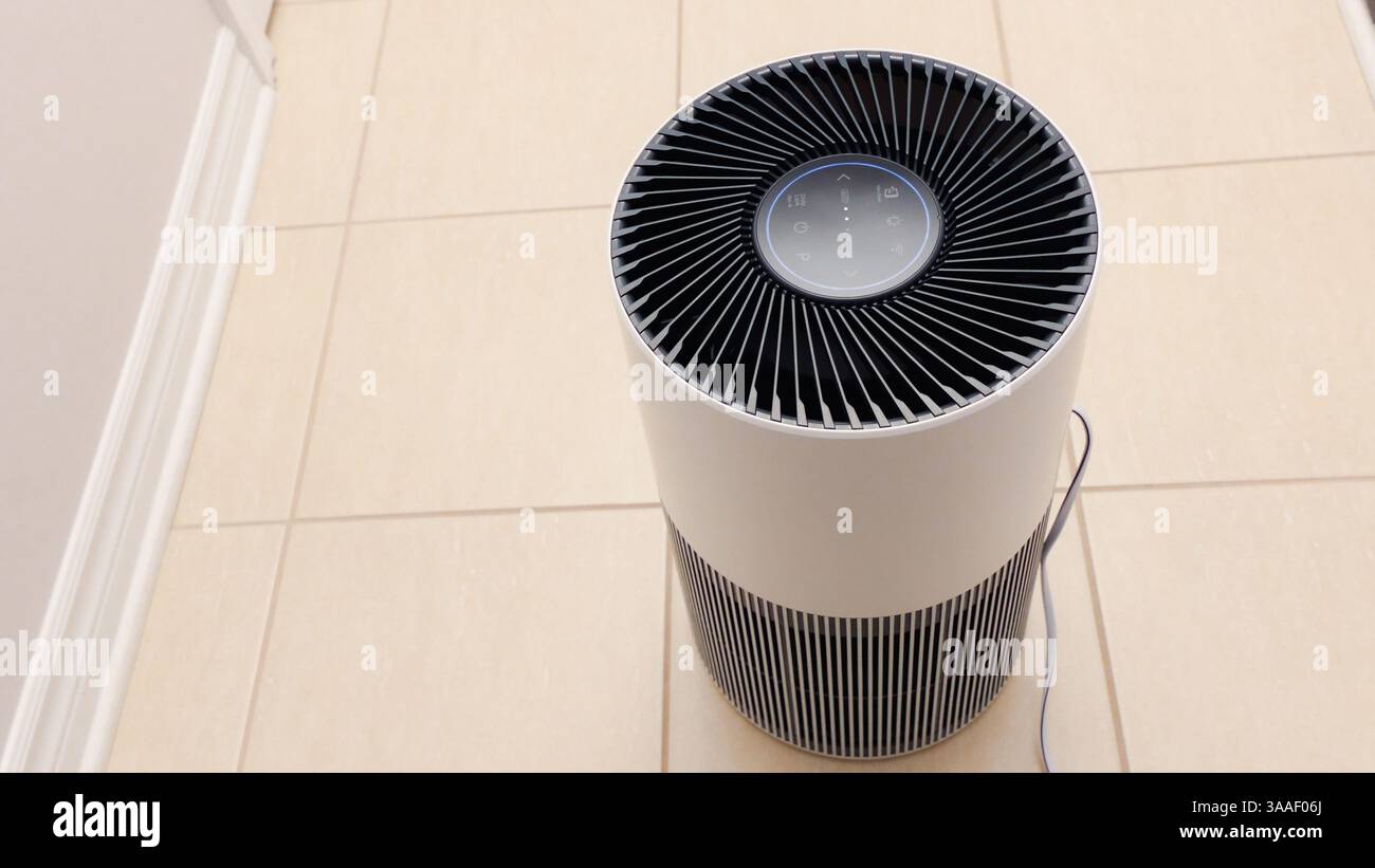 Vue rapprochée du purificateur d'air avec ventilateur noir. Appareil électronique rond noir avec boutons et lumières brillantes sur fond blanc. Banque D'Images
