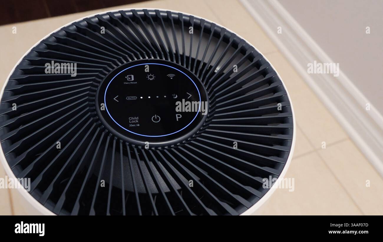 Vue rapprochée du purificateur d'air avec ventilateur noir. Appareil électronique rond noir avec boutons et lumières brillantes sur fond blanc. Banque D'Images