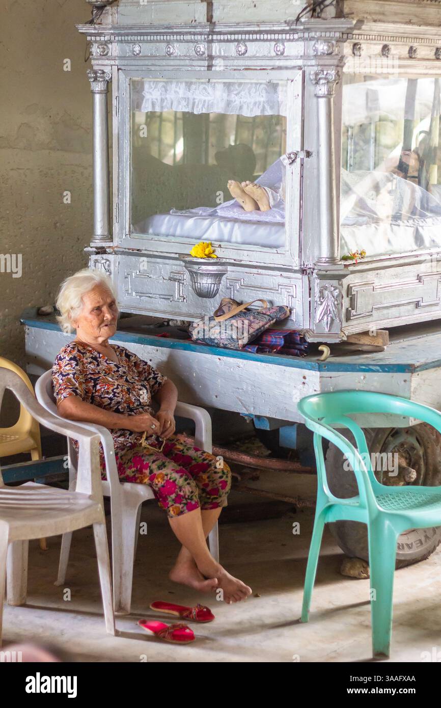 Une vieille femme est assise à côté de Santo Intierro image à l'intérieur d'une église de la ville de Camiguin, Philippines lors d'un événement religieux Banque D'Images