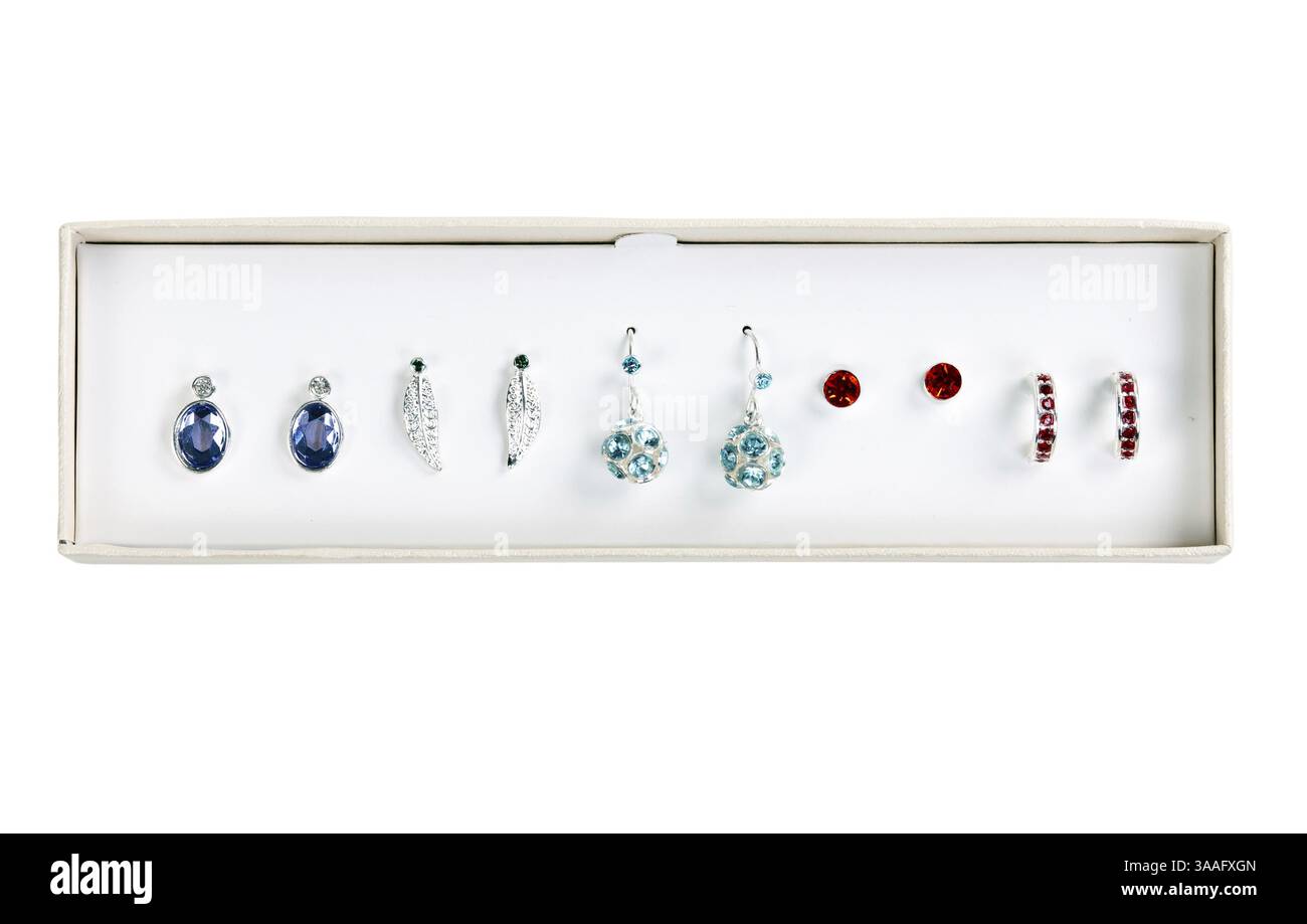Cinq paires de boucles d'oreilles avec des pierres dans une boîte en carton sur un fond blanc Banque D'Images