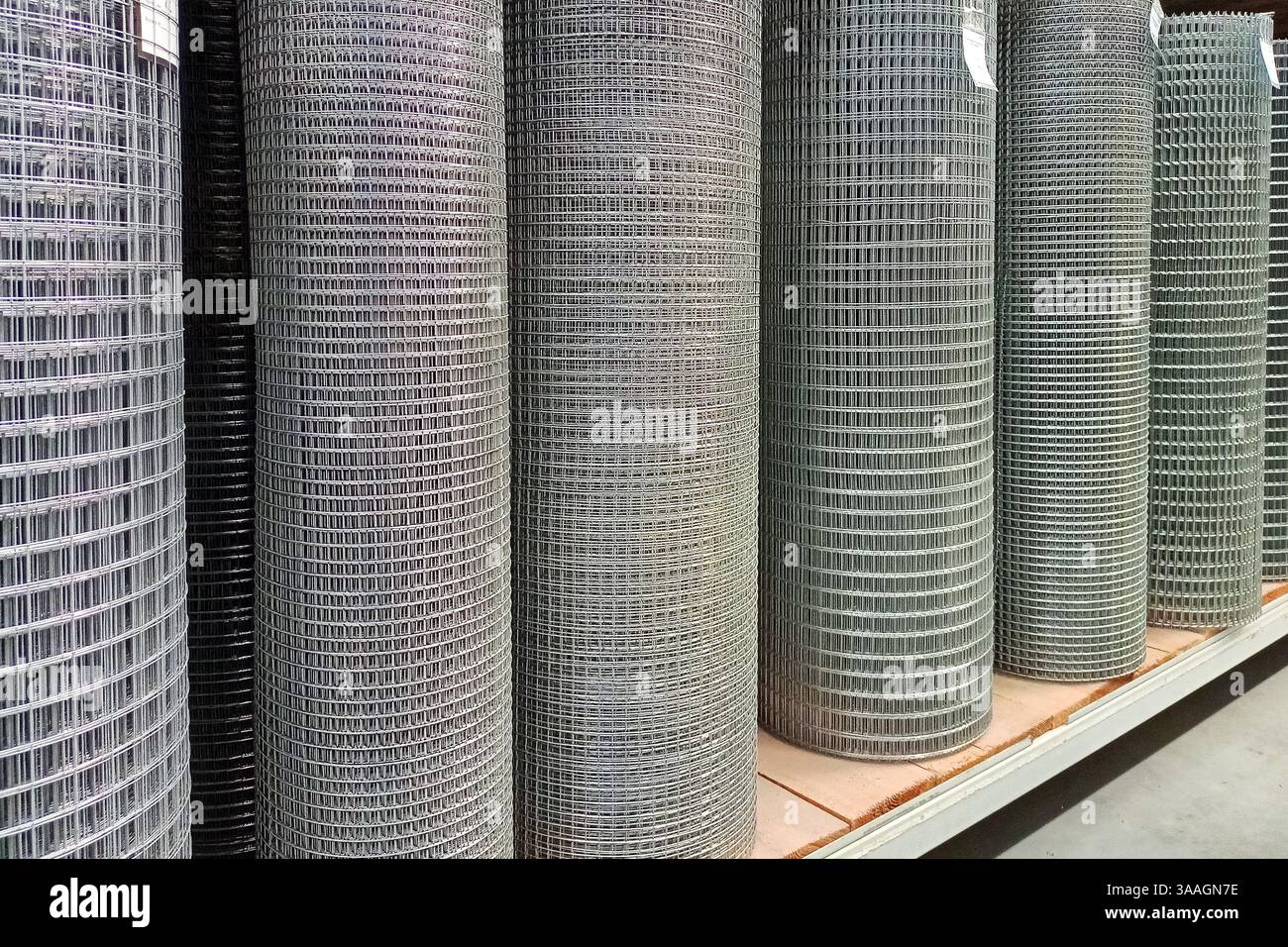 Grandes piles de rouleaux de treillis métallique industriels soigneusement disposés sur des étagères de stockage dans un entrepôt, capturant l'essence de l'ordre et de l'organisation pour les inconvénients Banque D'Images