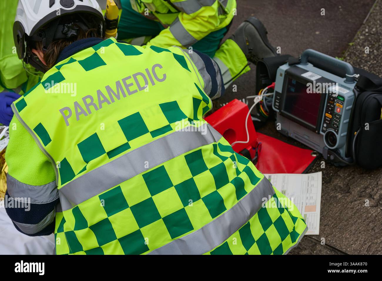 Ambulanciers paramédicaux prodiguant des soins d'urgence à un patient couvert d'une couverture thermique. Équipe médicale en uniformes haute visibilité utilisant un équipement professionnel Banque D'Images
